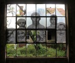 The faces of young immigrants peer through a shattered window.