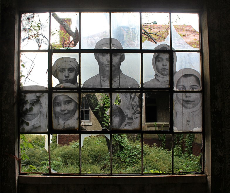 The faces of young immigrants peer through a shattered window.